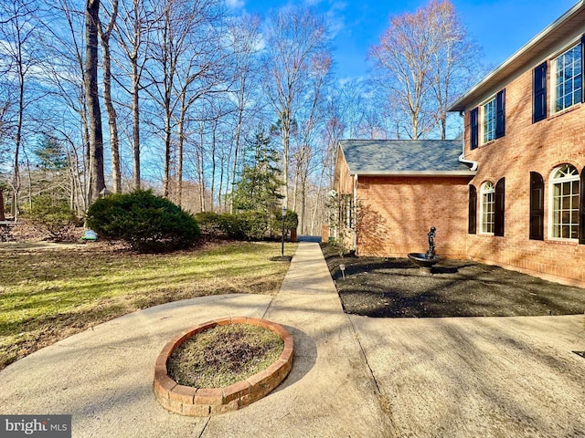 view of side of property featuring brick siding, a lawn, and roof with shingles