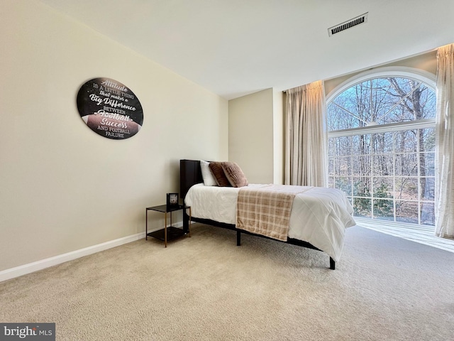 bedroom featuring baseboards, visible vents, and light colored carpet