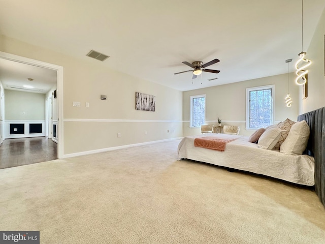 carpeted bedroom featuring ceiling fan, visible vents, and baseboards