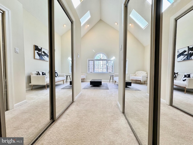 hall with high vaulted ceiling, recessed lighting, light carpet, a skylight, and baseboards