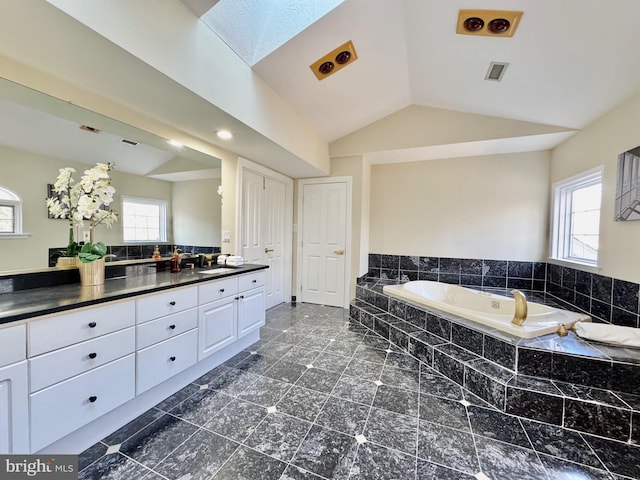 full bath with a healthy amount of sunlight, vaulted ceiling, a bath, and vanity