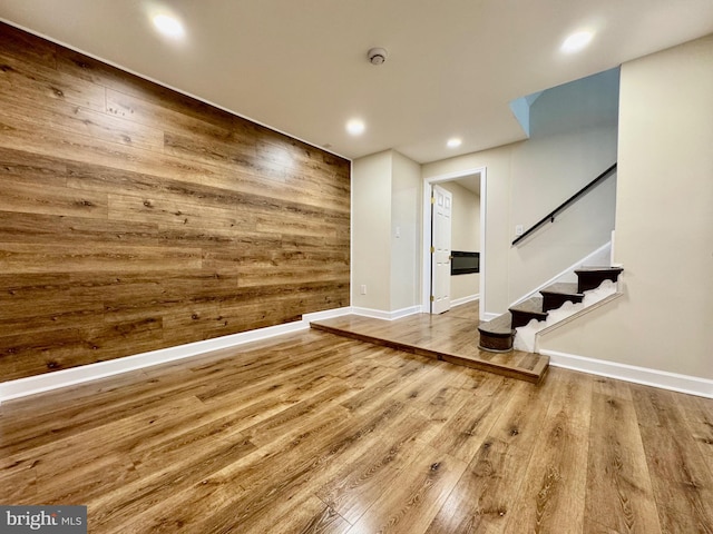 interior space featuring recessed lighting, wooden walls, wood finished floors, baseboards, and stairway