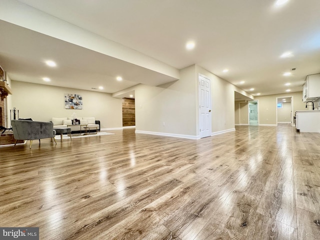 living room with light wood finished floors, a fireplace, baseboards, and recessed lighting