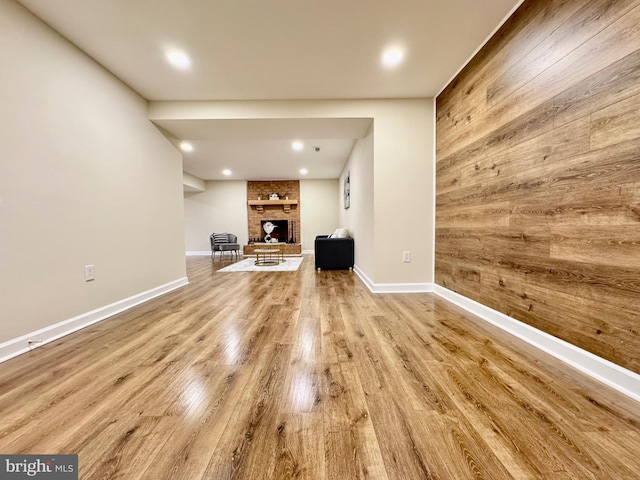 unfurnished living room with wood walls, light wood-style flooring, a fireplace, and baseboards