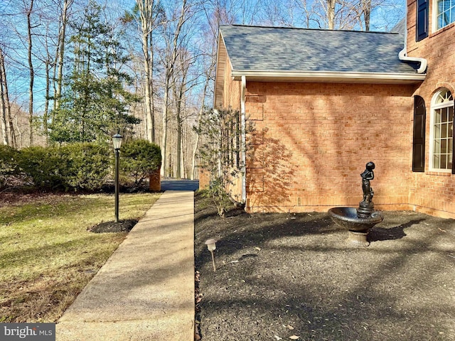 view of home's exterior featuring a shingled roof and brick siding