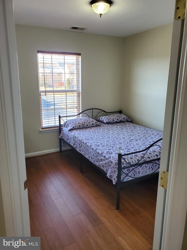 bedroom with visible vents, baseboards, and wood finished floors