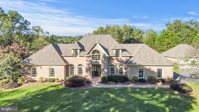 10928 Woodland Falls Dr, Great Falls, VA 22066 - french country inspired facade featuring a front lawn, brick siding, and roof with shingles