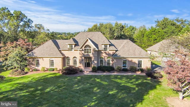 10928 Woodland Falls Dr, Great Falls, VA 22066 - french provincial home with a front yard, brick siding, and a shingled roof