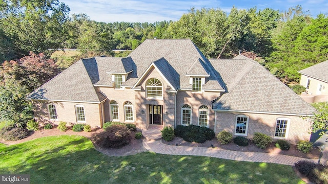 10928 Woodland Falls Dr, Great Falls, VA 22066 - french provincial home with a front yard, roof with shingles, and brick siding