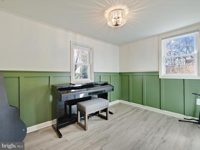 interior space featuring a wainscoted wall, light wood-type flooring, and crown molding