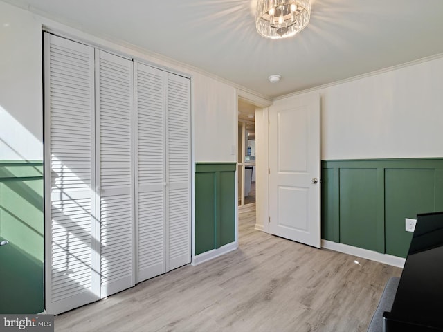 interior space featuring a wainscoted wall, crown molding, a decorative wall, and light wood finished floors