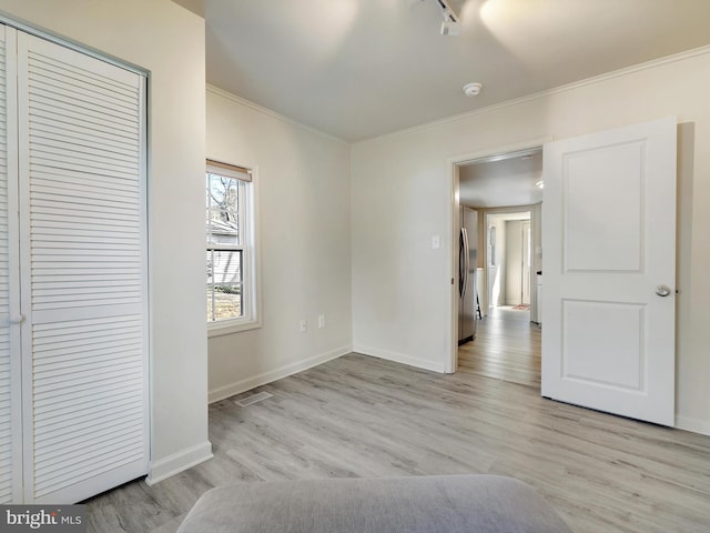 unfurnished bedroom with light wood-style floors, visible vents, crown molding, and baseboards