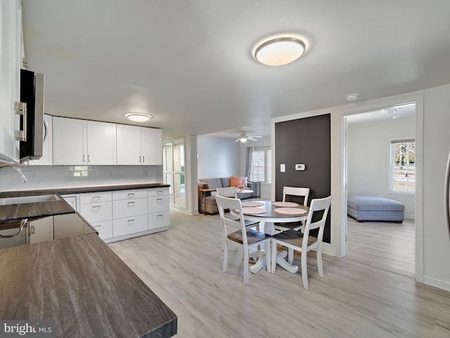 kitchen featuring tasteful backsplash, dark countertops, stainless steel microwave, open floor plan, and a sink