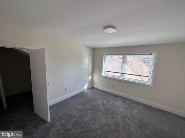 unfurnished bedroom with dark colored carpet and baseboards