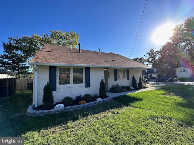 view of front of home featuring brick siding, a front yard, fence, and a shingled roof