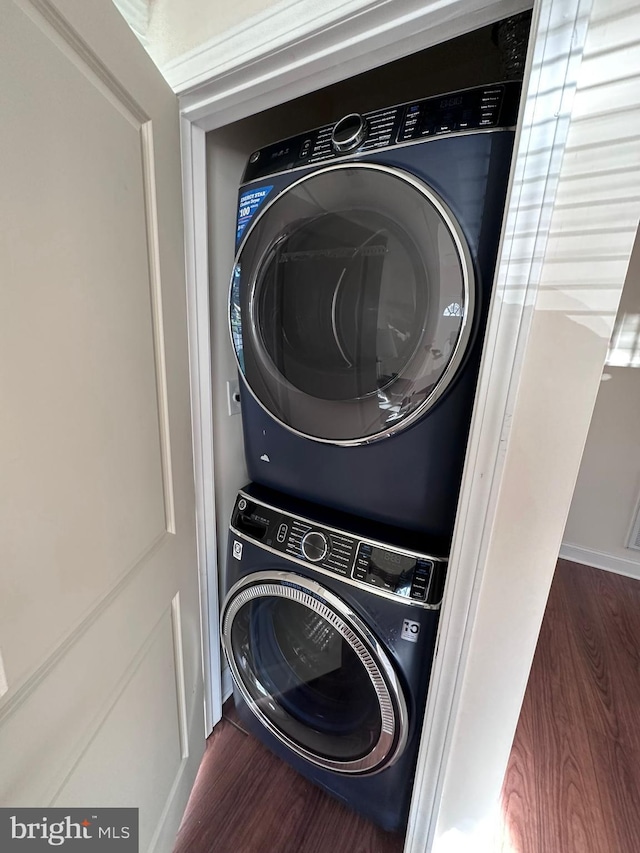 laundry room featuring stacked washer / dryer, laundry area, and wood finished floors