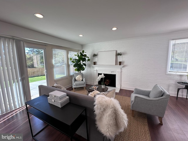 living area featuring recessed lighting, a fireplace, brick wall, and wood finished floors