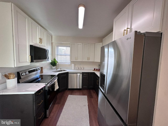 kitchen featuring dark wood-style flooring, a sink, white cabinets, light countertops, and appliances with stainless steel finishes