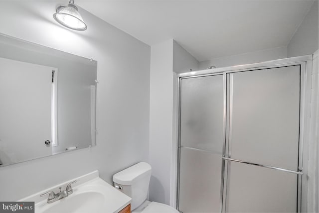 full bathroom with a shower with shower door, vanity, and toilet