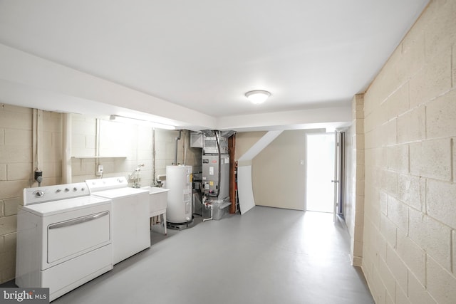 clothes washing area with concrete block wall, heating unit, water heater, separate washer and dryer, and laundry area