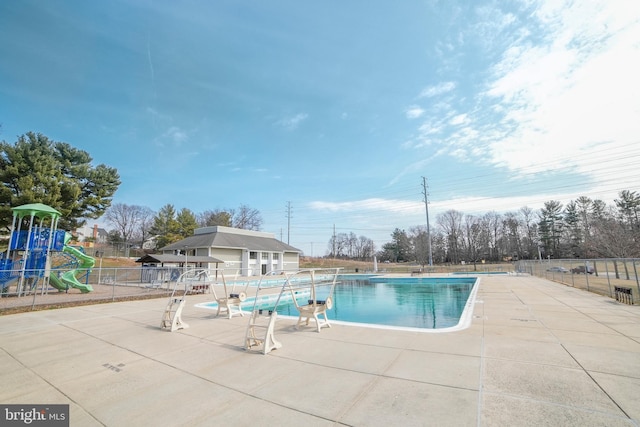 community pool featuring playground community, a patio, and fence