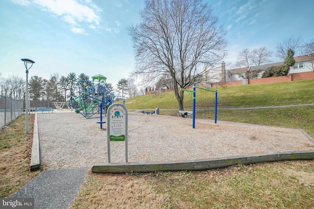 view of community featuring fence, playground community, and a yard