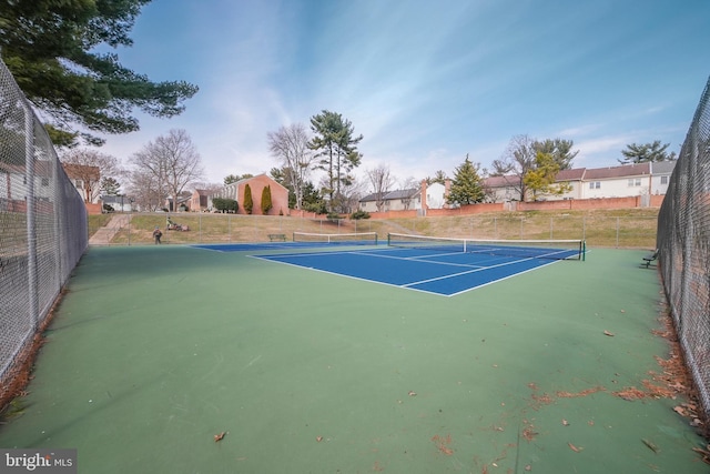 view of tennis court with a residential view and fence