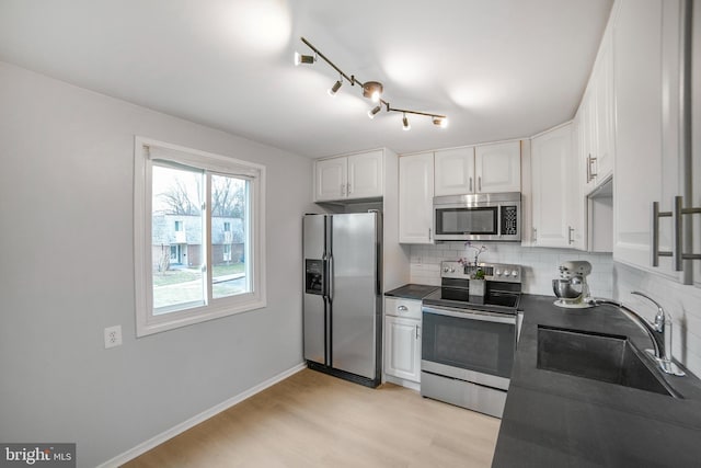 kitchen featuring dark countertops, tasteful backsplash, appliances with stainless steel finishes, and a sink