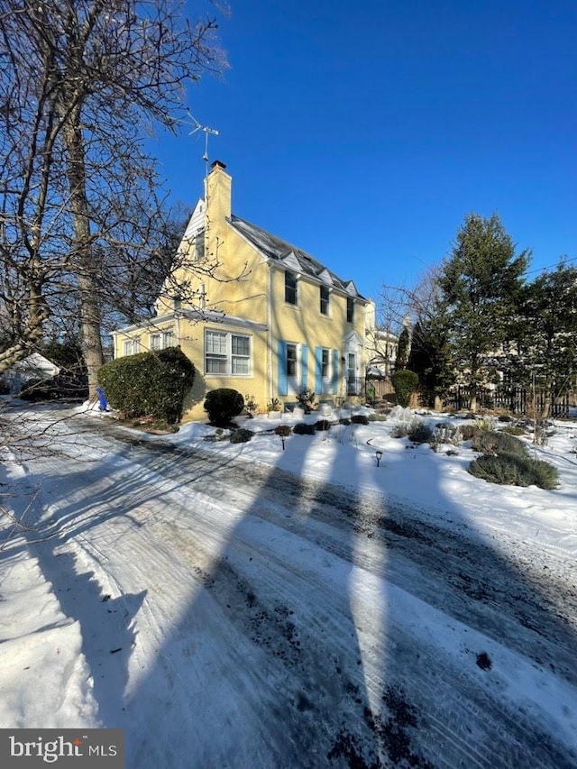 snow covered property with a chimney and stucco siding