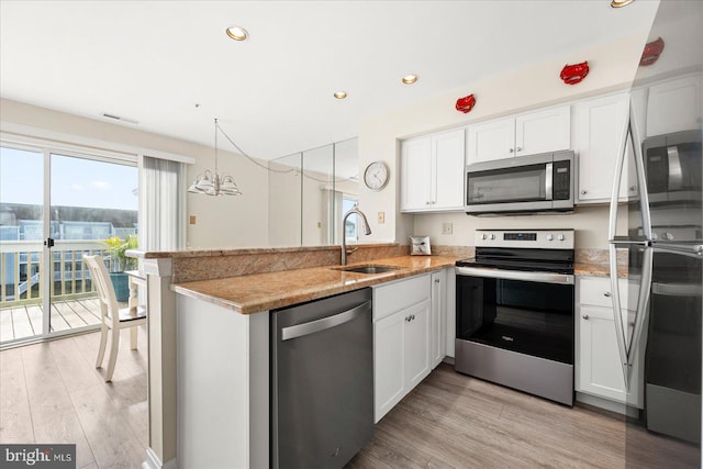 kitchen with sink, stainless steel appliances, white cabinetry, and kitchen peninsula