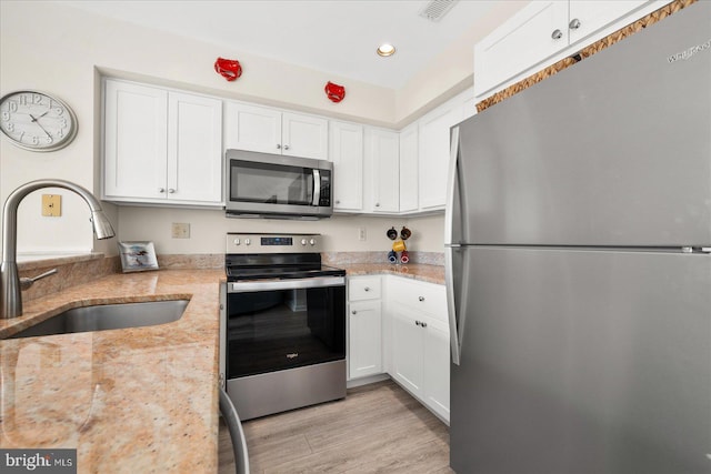 kitchen featuring white cabinetry, stainless steel appliances, light stone countertops, light hardwood / wood-style floors, and sink