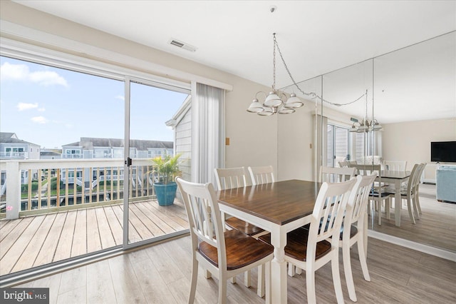 dining area with hardwood / wood-style floors and an inviting chandelier