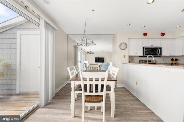 dining room with light hardwood / wood-style floors and a chandelier