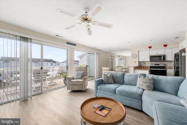 living room featuring ceiling fan, sink, and light hardwood / wood-style floors