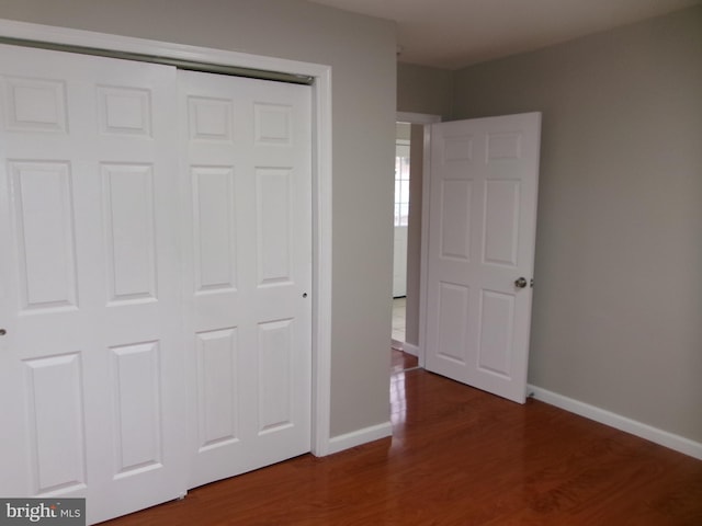 unfurnished bedroom with dark hardwood / wood-style floors and a closet