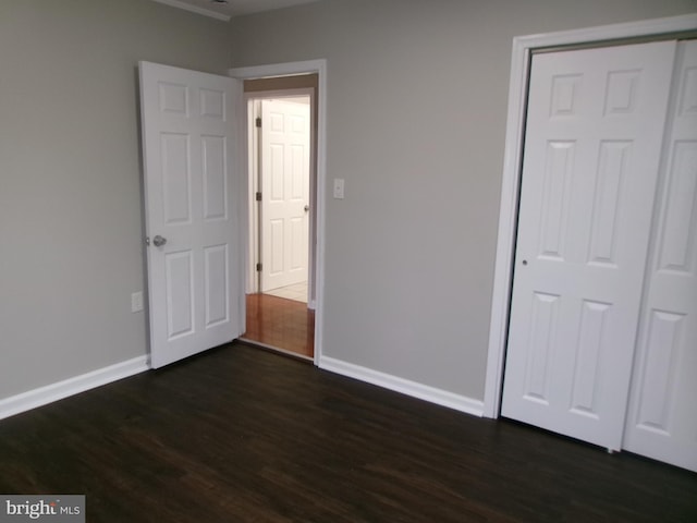 unfurnished bedroom with dark hardwood / wood-style flooring and a closet