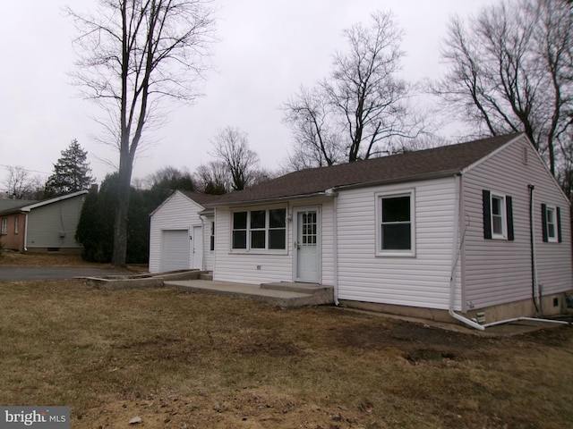 view of front of home featuring a garage, an outbuilding, and a front yard