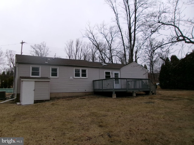 rear view of property with cooling unit, a yard, and a deck