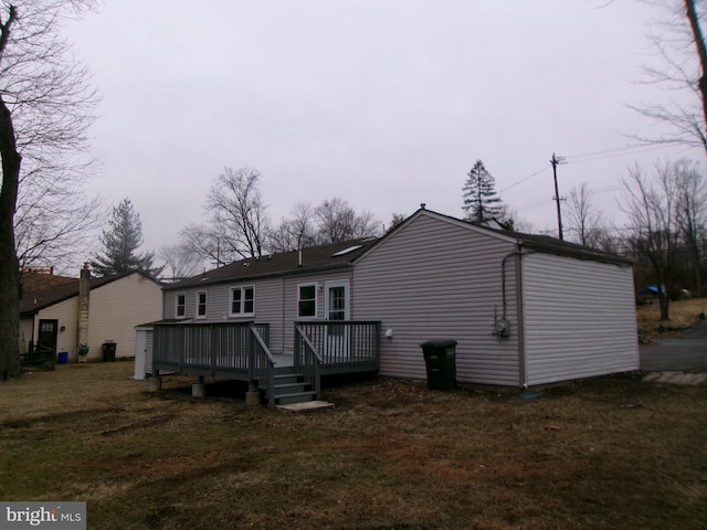 rear view of property featuring a deck and a lawn