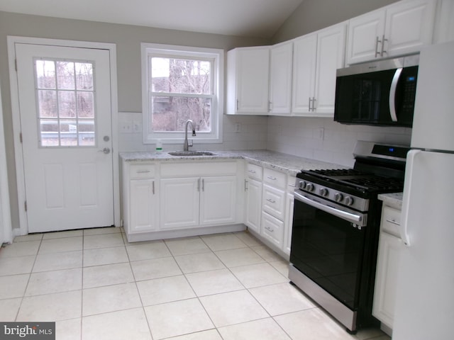 kitchen featuring appliances with stainless steel finishes, sink, lofted ceiling, white cabinets, and light stone countertops