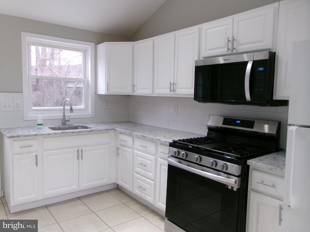 kitchen featuring stainless steel appliances, white cabinets, lofted ceiling, decorative backsplash, and sink