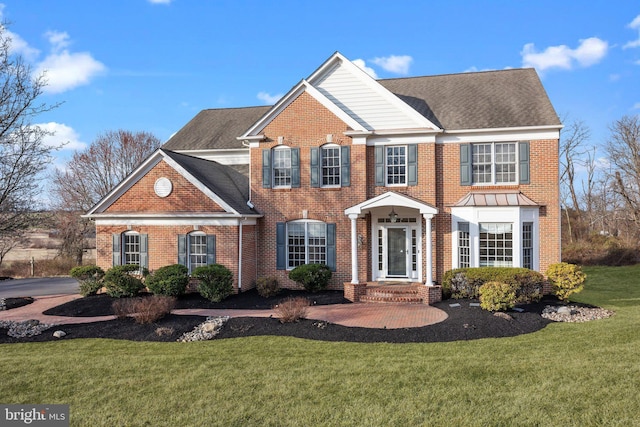 view of front of property with brick siding, roof with shingles, and a front yard