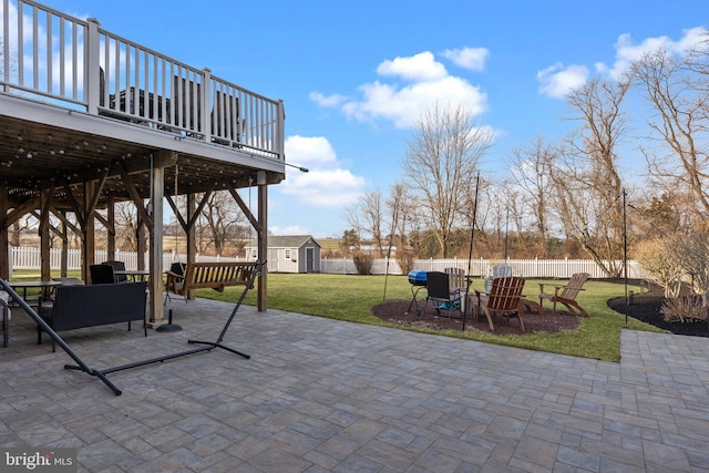 view of patio with an outbuilding, a deck, a fenced backyard, a fire pit, and a storage shed