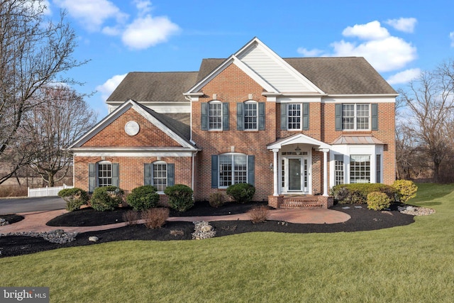 view of front of home featuring brick siding, a front lawn, and a shingled roof