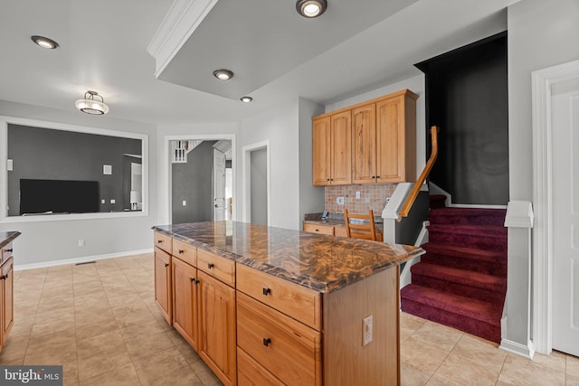 kitchen featuring dark stone counters, baseboards, tasteful backsplash, and a center island