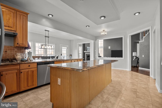 kitchen with a kitchen island, under cabinet range hood, decorative backsplash, dark stone countertops, and stainless steel dishwasher