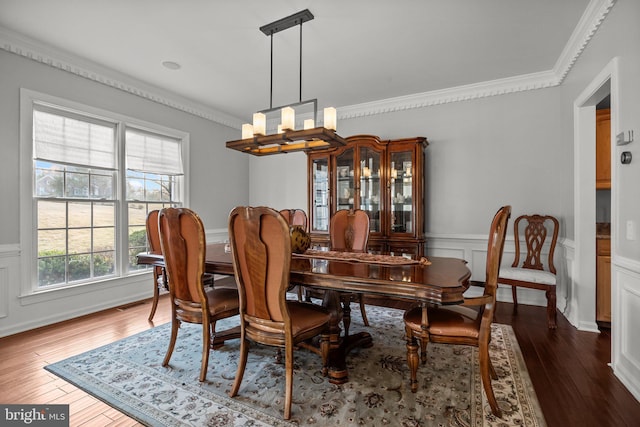 dining area with dark wood-style floors, a notable chandelier, and ornamental molding