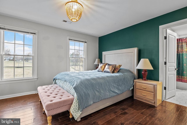 bedroom featuring visible vents, baseboards, dark wood-type flooring, and a chandelier