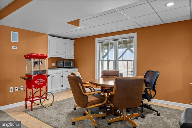 dining room featuring light tile patterned floors, a paneled ceiling, and baseboards