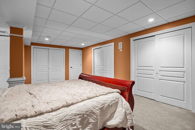 bedroom with recessed lighting, two closets, and light carpet